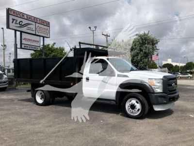 Ford F-450 XL dump truck in dealership lot, white cab, black dump bed, side view with crane logo watermark.