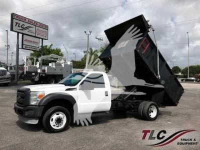 2014 Ford F450 XL dump truck with bed raised, white cab, black dump body, in a dealership lot.