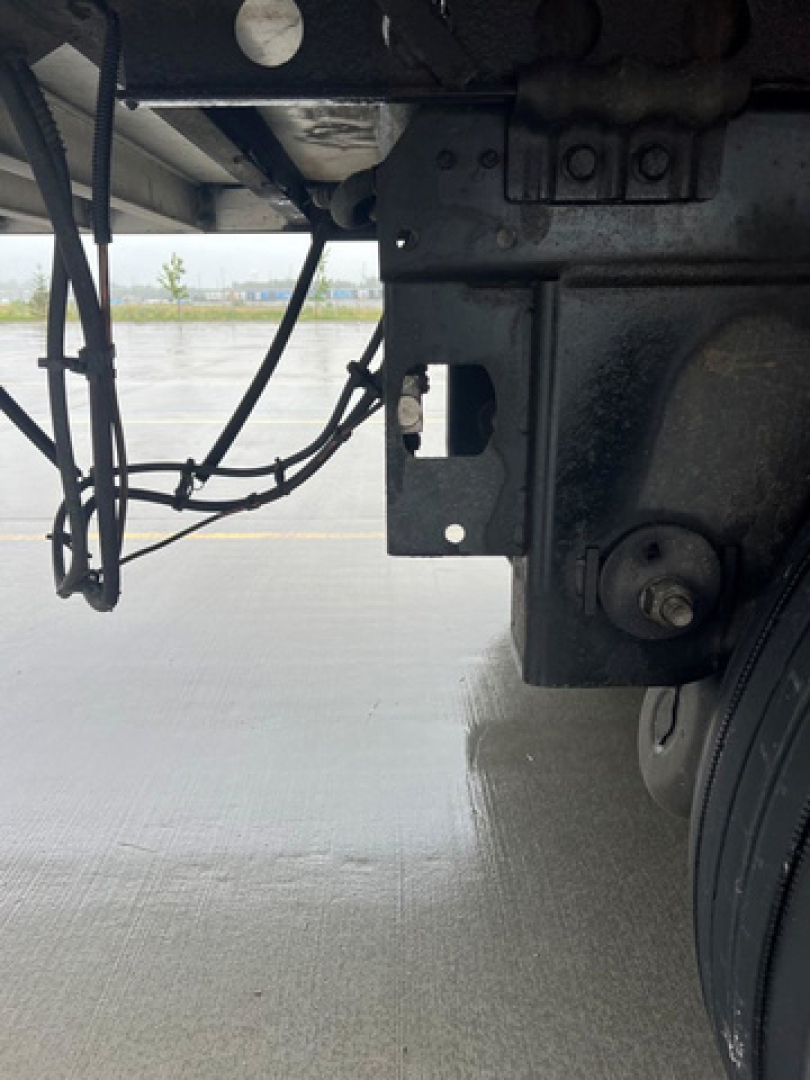 Trailer undercarriage view of 2014 Wabash refrigerated trailer showing suspension bracket and mounting hardware near wheel; visible hydraulic or electrical lines and frame components.