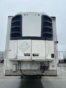 Reefer trailer at a yard showing front refrigeration unit with metal doors and control area.