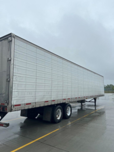 Reefer trailer showing side view with tandem axles and gray metal panels.