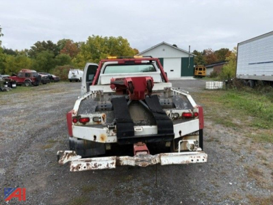 Tow truck bed with mounted crane equipment and straps in view, rear view of 1999 Ford F-450 tow truck
