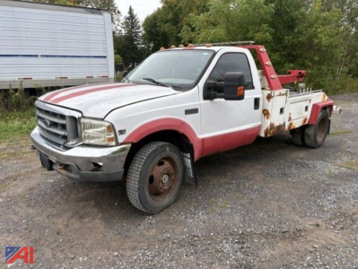 1999 Ford F-450 tow truck front-left view showing white body with red accents and rust on wheel wells and tow equipment.
