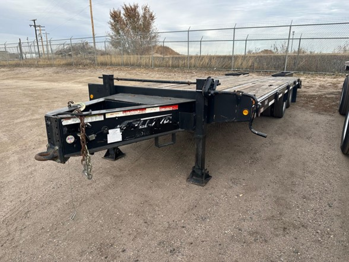 Flatbed trailer showing Felling FT-24-2 LP with black frame and low-profile support legs, rear hitch area, and chains visible.