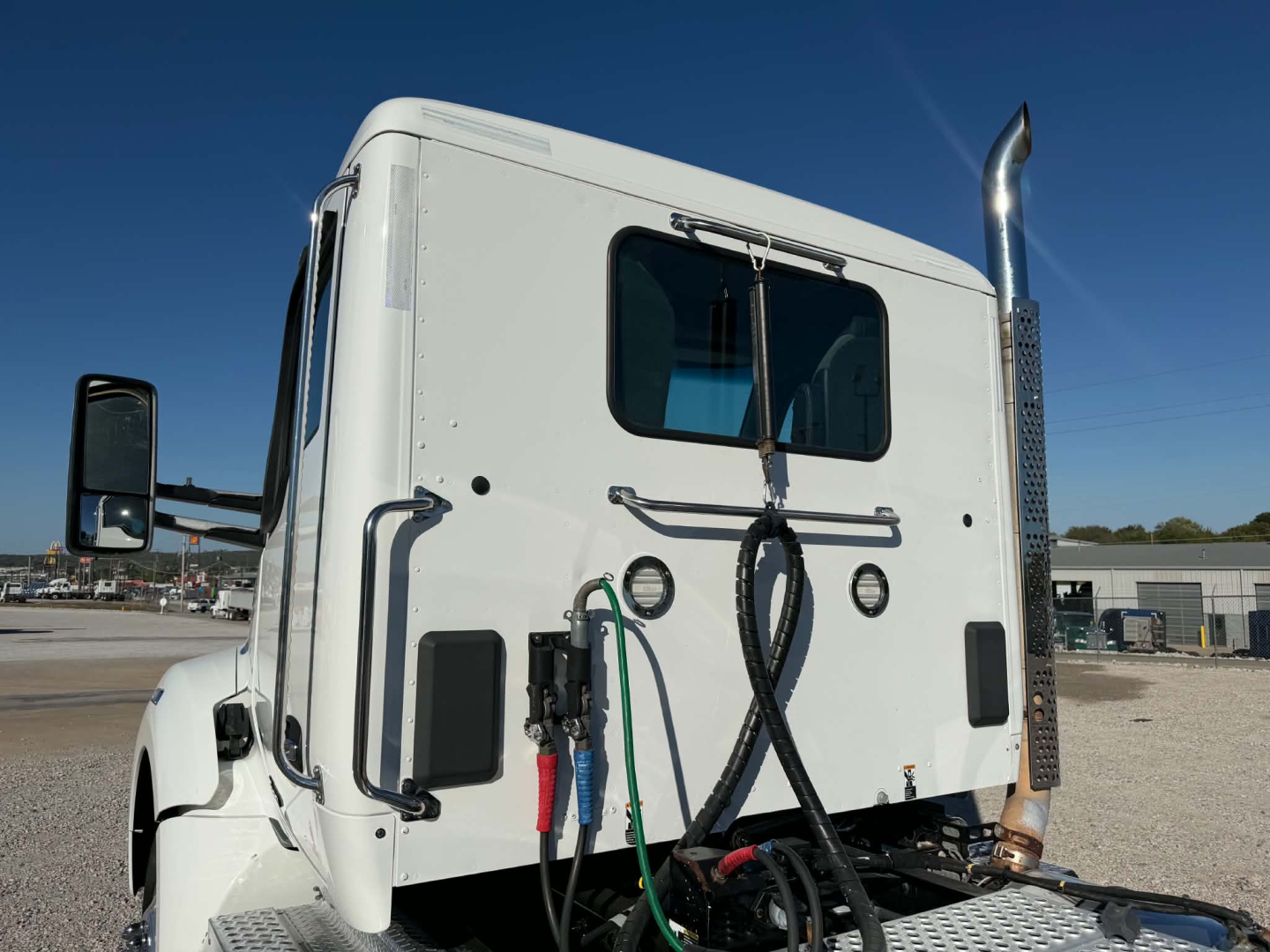Kenworth T880 truck cab rear view showing fuel lines and exhaust stack with hoses and wiring visible
