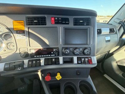 Kenworth T880 truck interior dash view showing steering wheel area, center display, climate controls, switches, and cup holders.