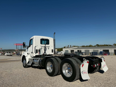 Kenworth T880 tractor rear view showing triple rear axles and white mud flaps with MHC logo.