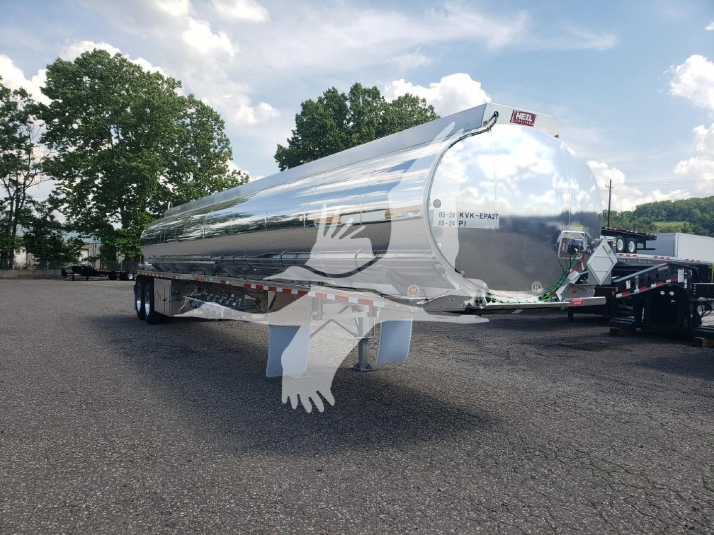 Trailer tank showing polished aluminum surface with rear and side view. Visible text includes Heil logo on the back and small labels on the rear end.