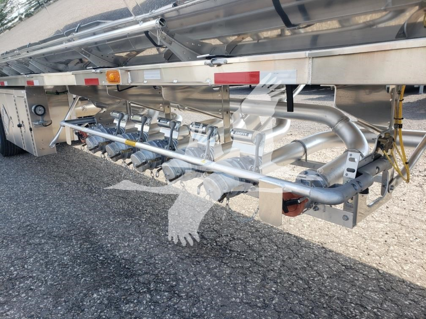 Trailer undercarriage showing polished stainless steel piping and valves, with hoses and mounting brackets, part of a Heil 406A Petro trailer.
