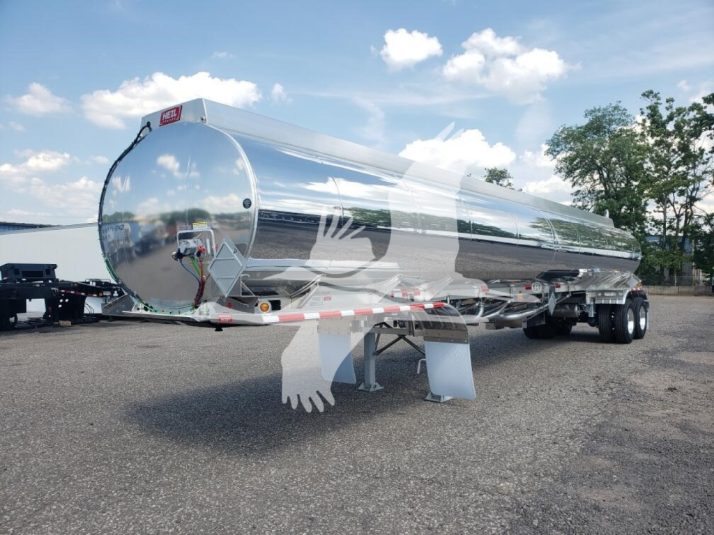 Heil 406A Petro-5C tanker trailer with polished aluminum cylindrical tank and dual rear axles, front support legs visible.