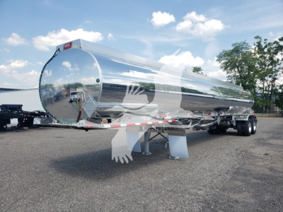 Heil 406A Petro-5C tanker trailer with polished aluminum cylindrical tank and dual rear axles, front support legs visible.