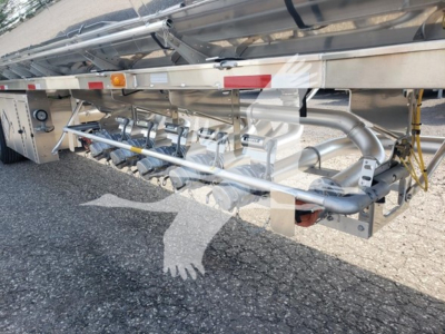 Trailer undercarriage showing metal piping and fittings along frame with reflective tape and hydraulic lines.