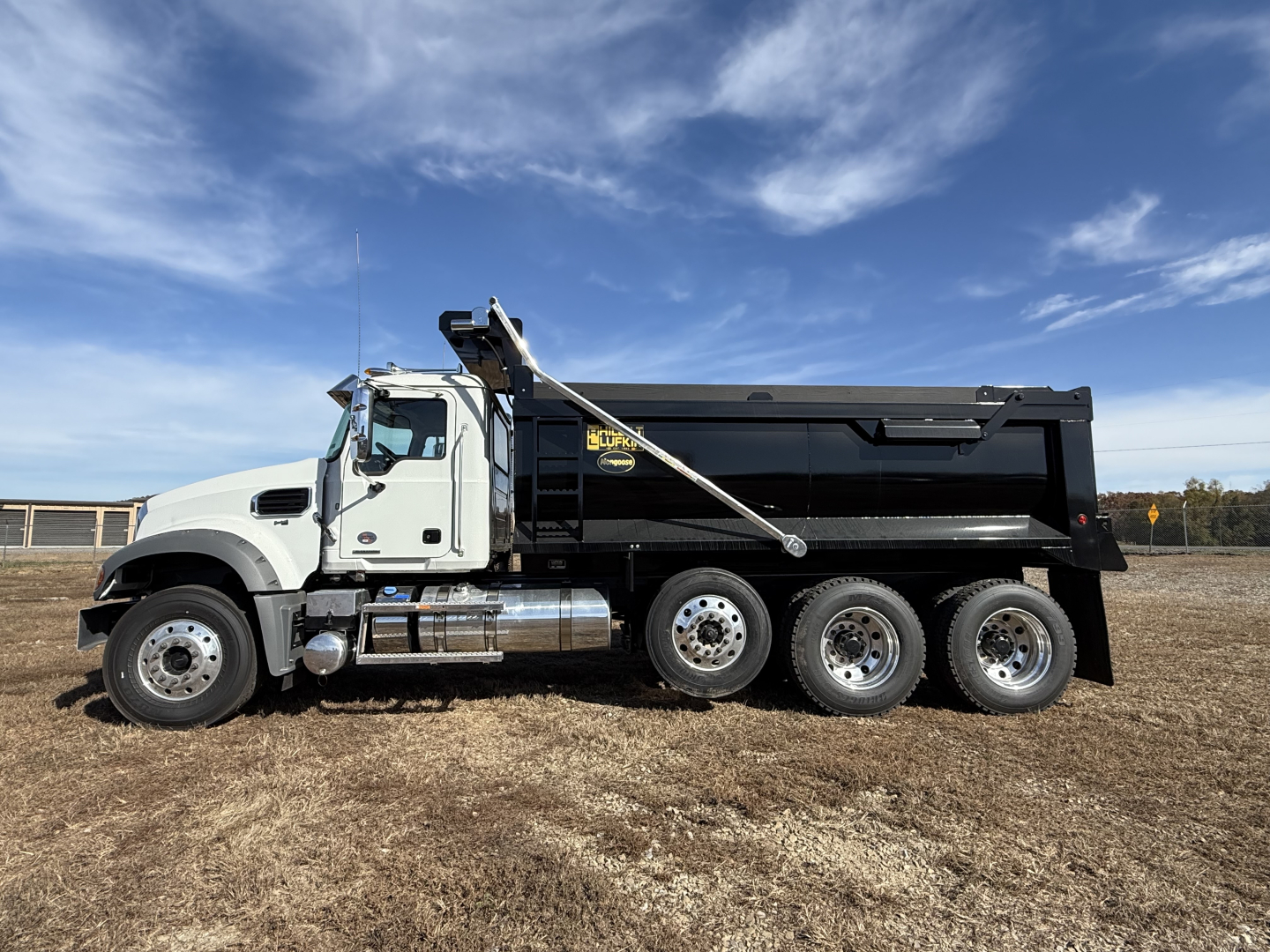 Dump truck showing Mack GR84F chassis with six-wheel configuration and black dump bed.