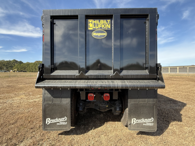 Dump truck bed rear view showing Mack GR84F new with black hull, Haliburton Lufkin Mongoose sticker, rear bumper, red taillights, and Bruckner mudflaps.