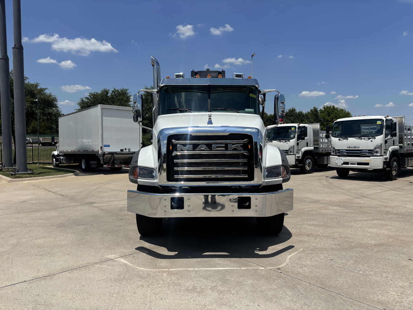 Mack GR64B roll-off truck front view showing chrome grille and bumper with stacked headlights.