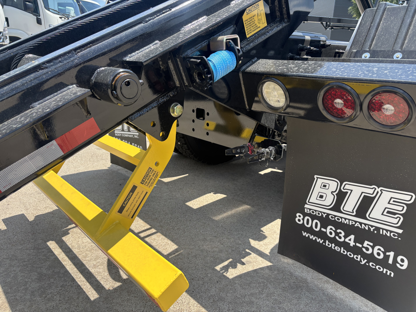 Mack GR64B roll-off truck chassis showing yellow support leg and hydraulic components with BTE Body Company branding visible on the side.