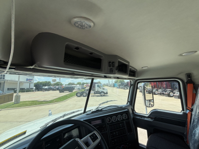 Cab interior of a 2026 Mack GR64B roll-off truck showing dashboard, steering wheel, and overhead storage compartments