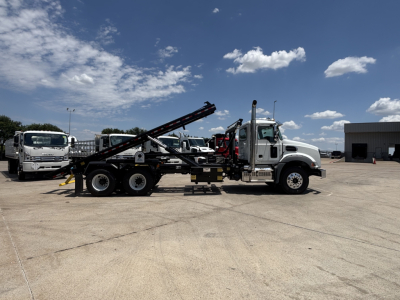 2026 Mack GR64B rolloff truck in an outdoor lot showing side profile with hydraulic arm and metal ramp.