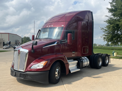 Kenworth T680 tractor in maroon showing front grille, headlights, and side cab; chrome fuel tanks and steps visible; alloy wheels; no visible text on the vehicle itself.