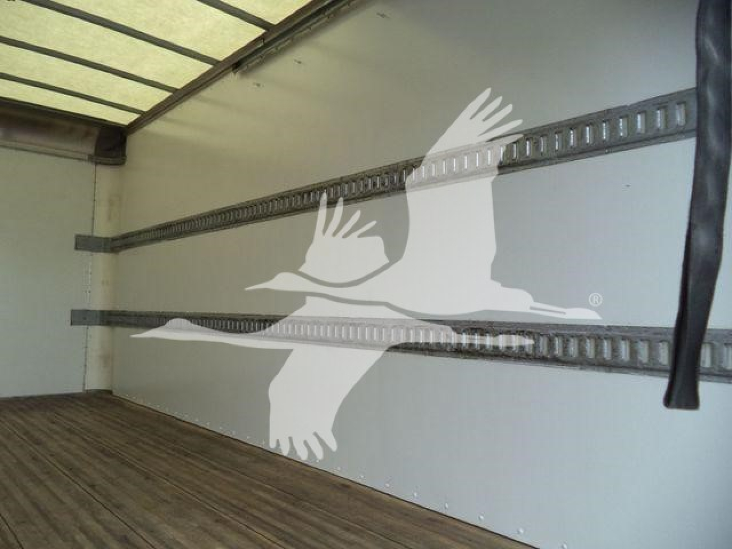 Isuzu NPR HD truck box interior showing wall and tie-down rails with a partially visible black strap.