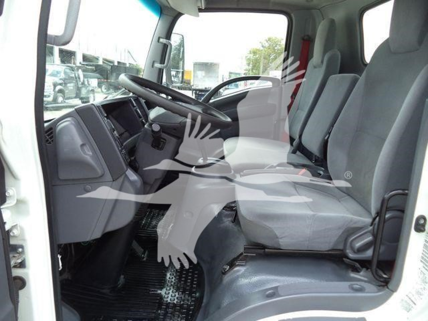 Isuzu NPR HD truck cab interior, front seats and dashboard visible from open door, steering wheel on left, gray upholstery.