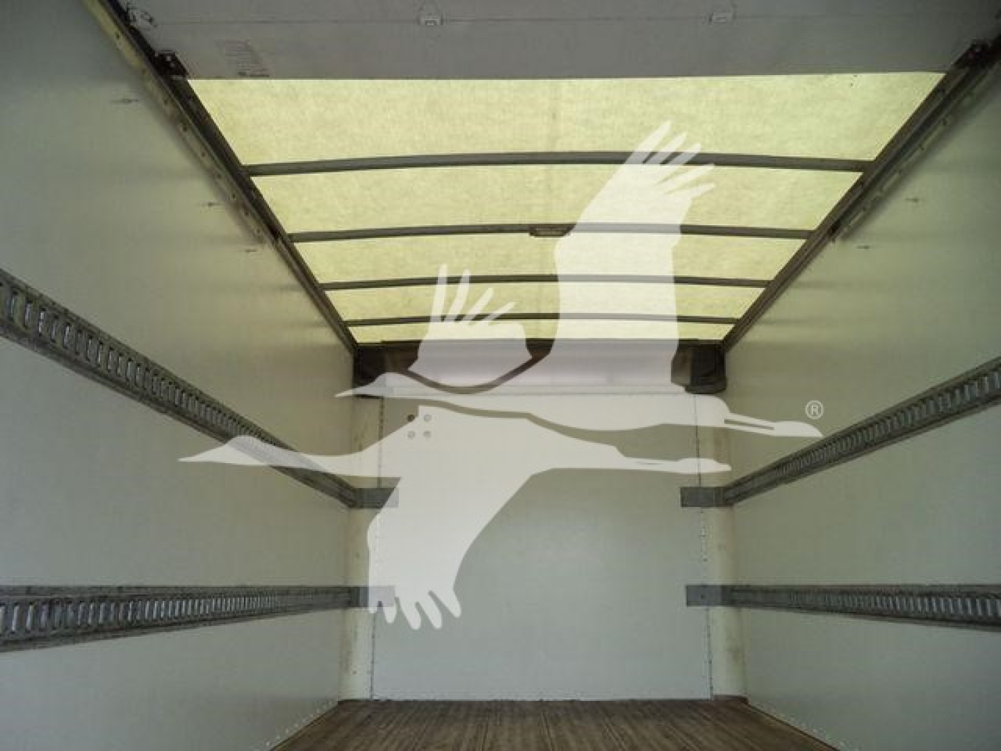 Trailer/box truck cargo area with metal E-track rails on both sides and wooden floor, empty interior