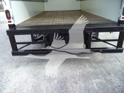 Isuzu NPR HD box truck rear view showing open cargo area and black steel ramp with TLC markings.