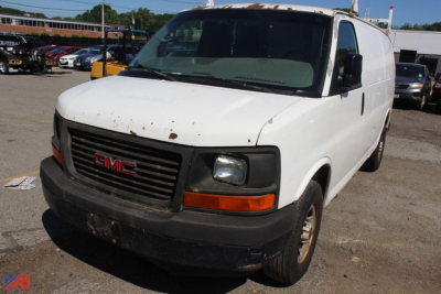 GMC Savana full-size cargo van front-left view showing grille with red GMC badge and headlight assembly.