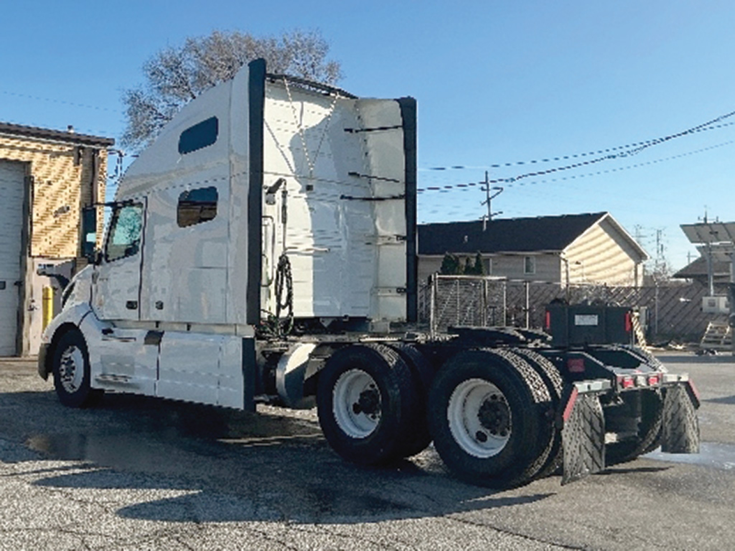 Volvo VNL 760 tractor in-cab view from rear-left showing sleeper cab, dual rear axles, and fifth-wheel with chrome fuel tanks.