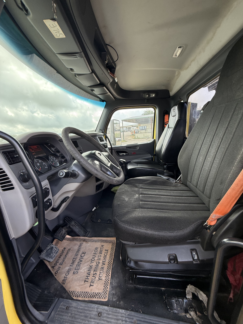 Cab interior of a 2017 Peterbilt 579 dump truck showing steering wheel, driver seat, and dashboard with floor mats.
