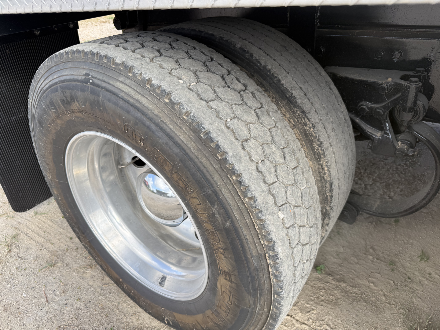 Truck axle and dual rear tires of a 2017 Peterbilt 579 dump truck showing tire tread and wheel assembly.