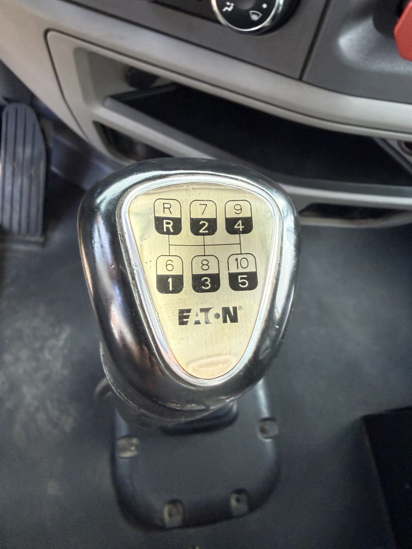 Gear selector knob with 10-speed Eaton shift pattern labeled R, 1, 2, 3, 4, 5, 6, 8, 9, 10 on a Peterbilt truck cab interior.