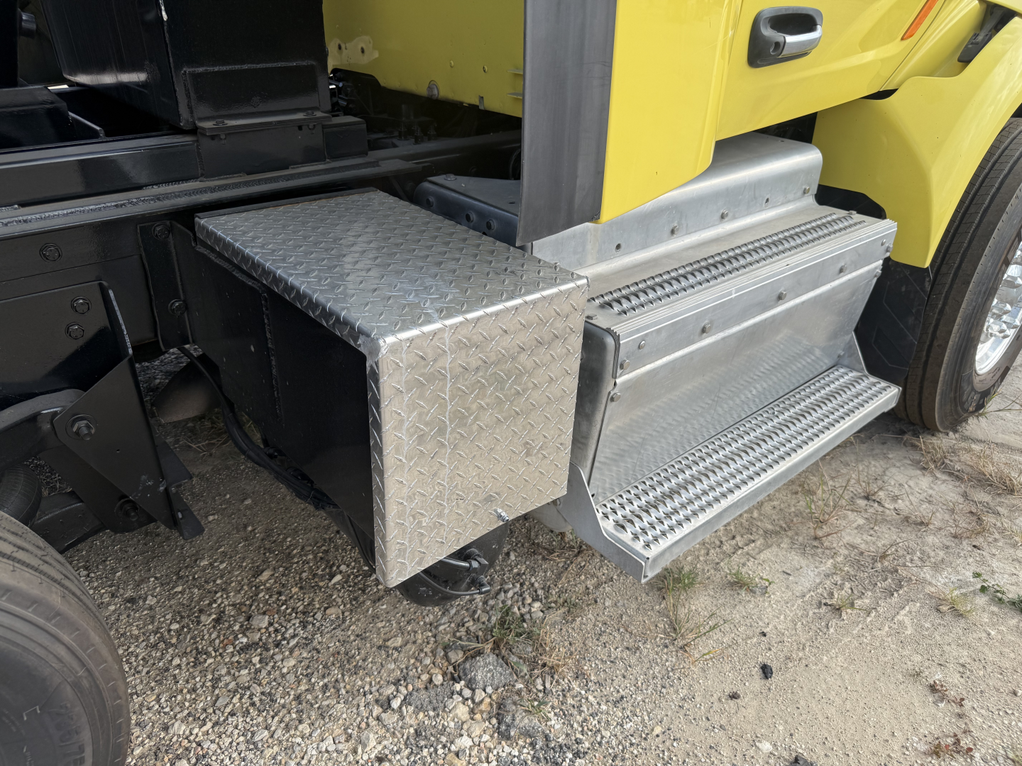 Truck steps and toolbox on a Peterbilt 579 dump truck showing diamond plate aluminum toolbox adjacent to the cab and metal steps.