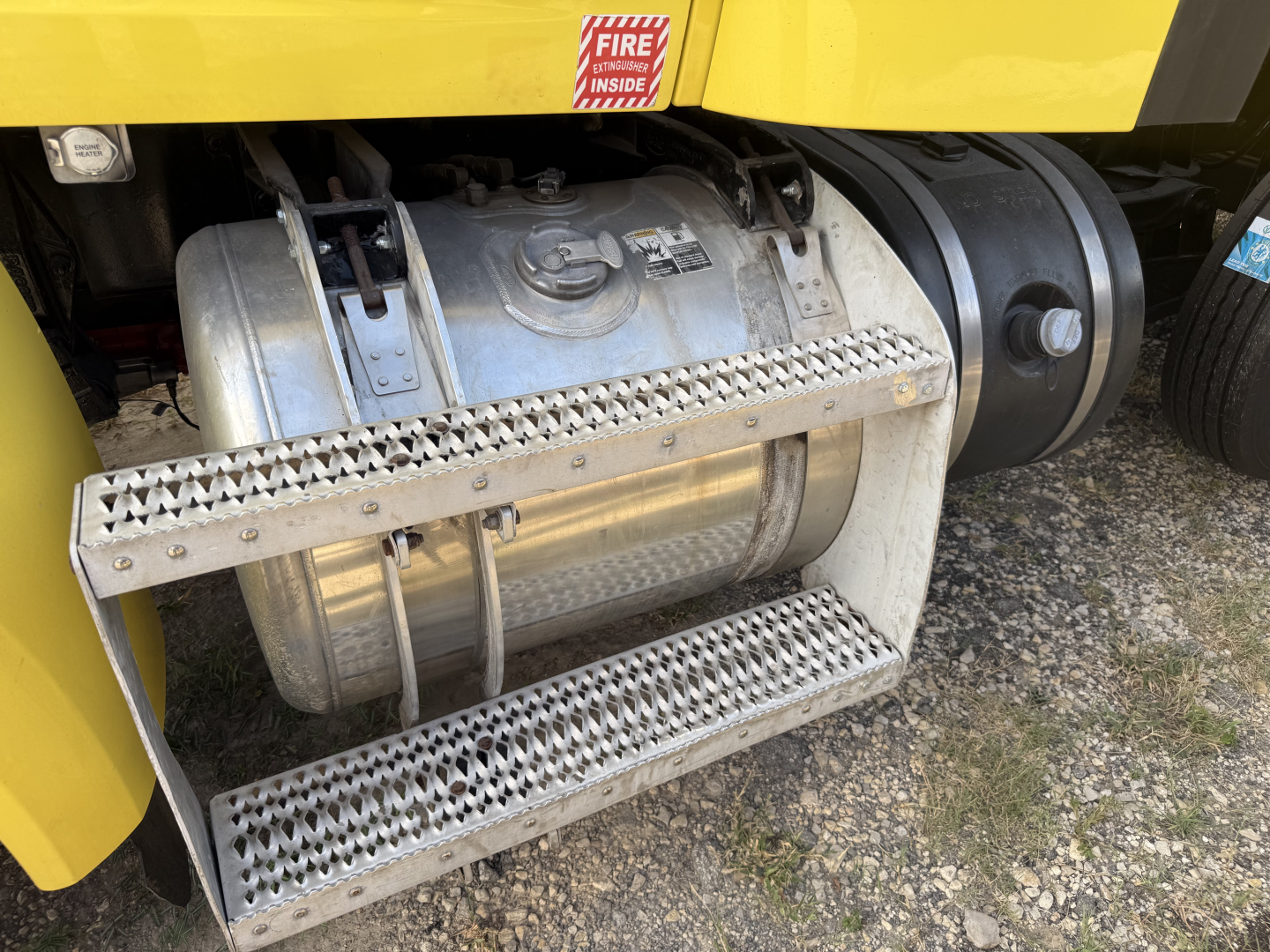 Truck fuel tank and side step of a 2017 Peterbilt 579, showing metal cylindrical fuel tank, perforated metal side steps, and surrounding chassis.