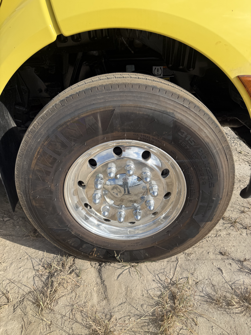Truck wheel on a Peterbilt 579 dump truck showing a polished shiny rim with lug nuts and tire; no legible brand text visible on tire.