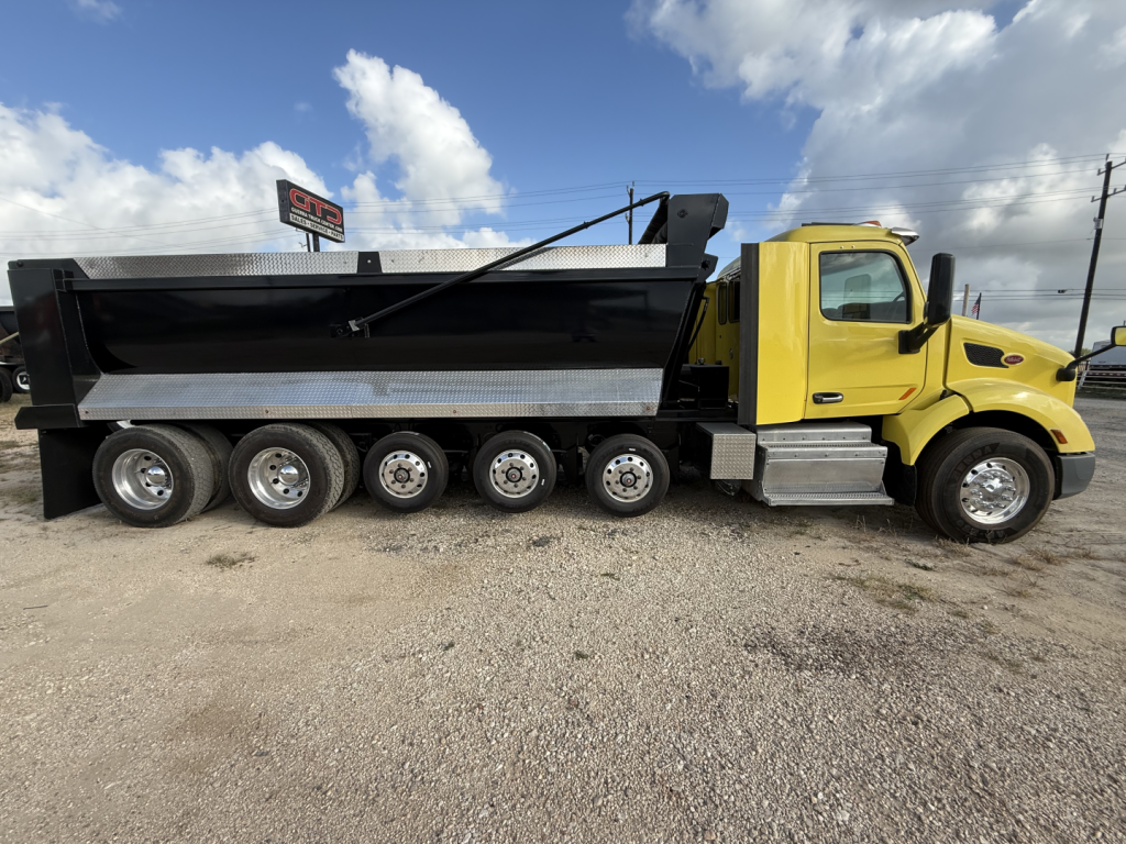 Peterbilt 579 dump truck in service showing side view with yellow cab and black dump bed, multiple rear axles, VIN 1XPBDP9X0HD410466 in listing.