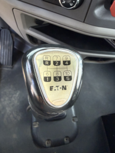 Gear selector knob with 10-speed Eaton shift pattern labeled R, 1, 2, 3, 4, 5, 6, 8, 9, 10 on a Peterbilt truck cab interior.