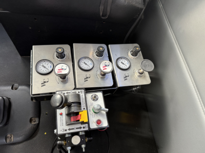 Panel with three boxed gauges and a control switch in a Peterbilt cab area showing W, R, and left/right labels; small toggle switch and handle nearby