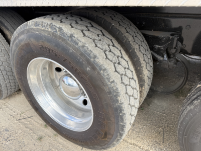 Truck axle and dual rear wheels showing tire tread and chrome wheel, undercarriage components visible.