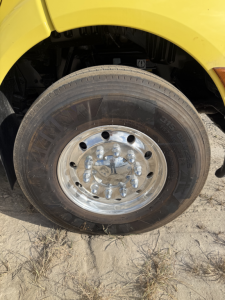 Truck wheel on a Peterbilt 579 dump truck showing a polished shiny rim with lug nuts and tire; no legible brand text visible on tire.