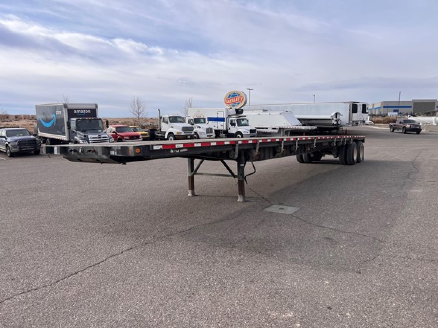 Flatbed trailer with tandem axles and slider steel deck in an outdoor lot, showing support legs and rear wheels, 2014 Fontaine closed tandem w slider steel flatbed