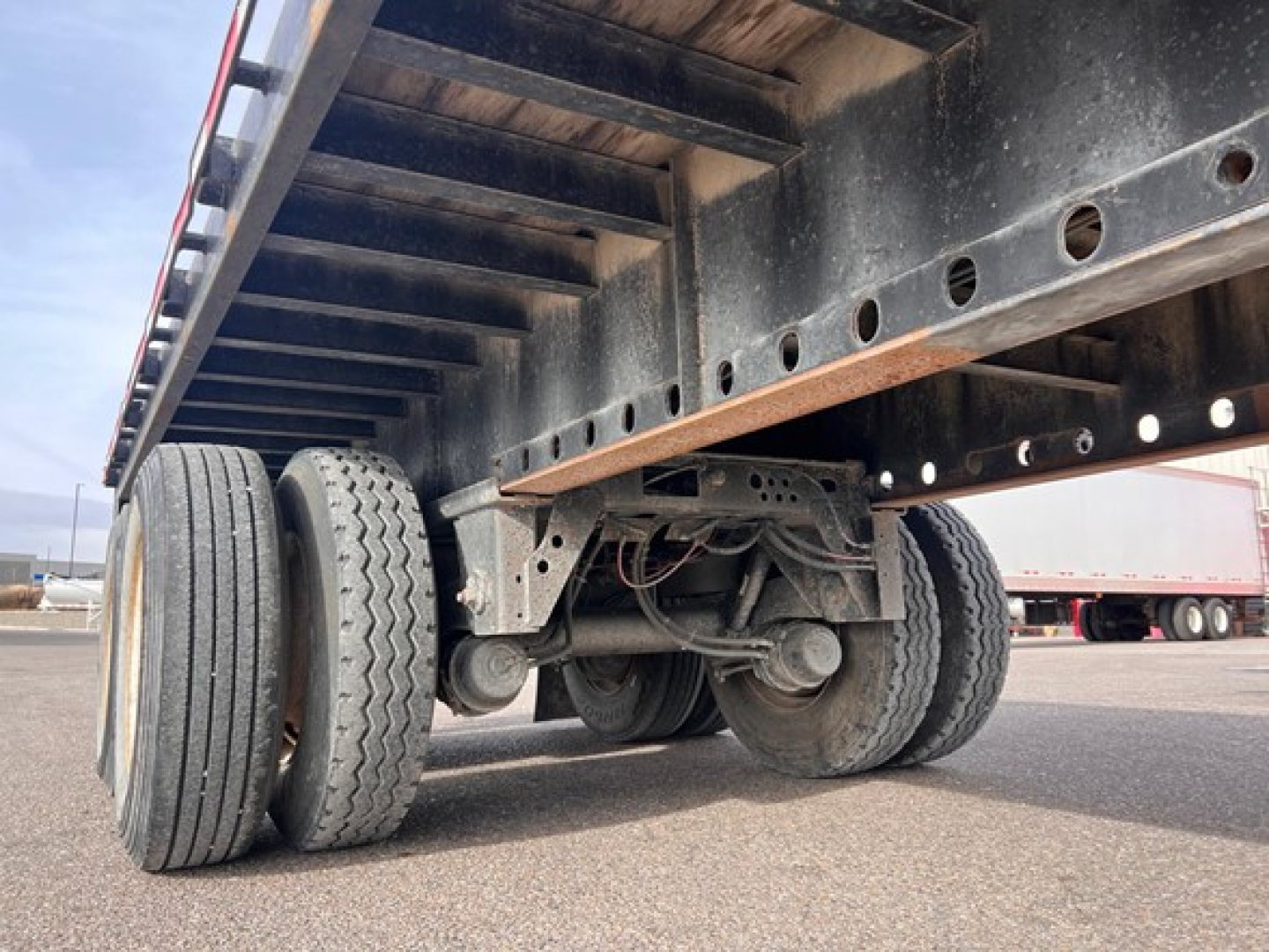 Trailer undercarriage of a 2014 Fontaine flatbed showing dual rear tandems with steel frame and mounted suspension components.