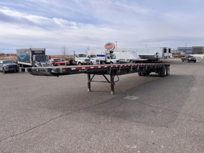 Flatbed trailer with tandem axles and slider steel deck in an outdoor lot, showing support legs and rear wheels, 2014 Fontaine closed tandem w slider steel flatbed