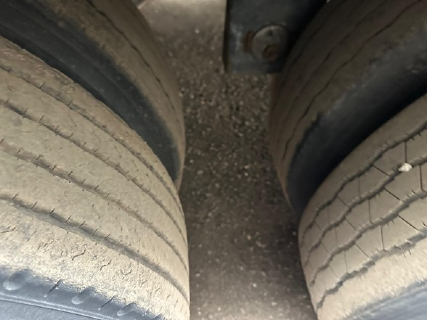Dual rear trailer wheels with worn tires and grime showing undercarriage.