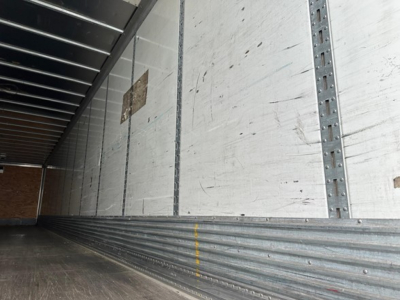 Trailer interior with metal side walls and ribbed floor showing a long empty cargo area.