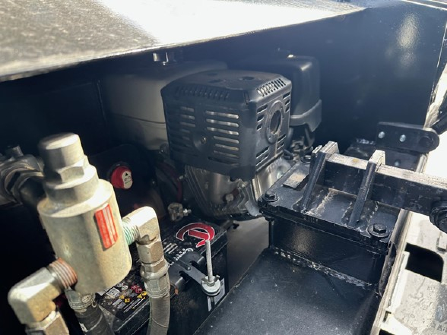 Trailer engine bay showing small gasoline engine with air filter housing, hydraulic reservoir, and control levers in a Load King trailer chassis.