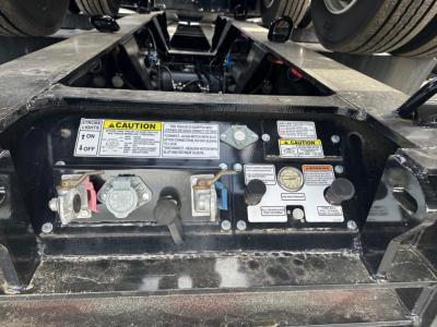 Trailer management panel with various valves and warning labels on Load King lowboy trailer showing control levers and gauges.
