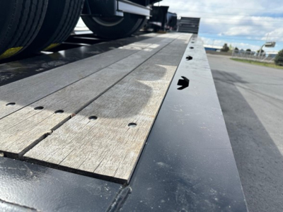Load King lowboy trailer deck with wooden boards and steel edge, side view showing surface details and fasteners.