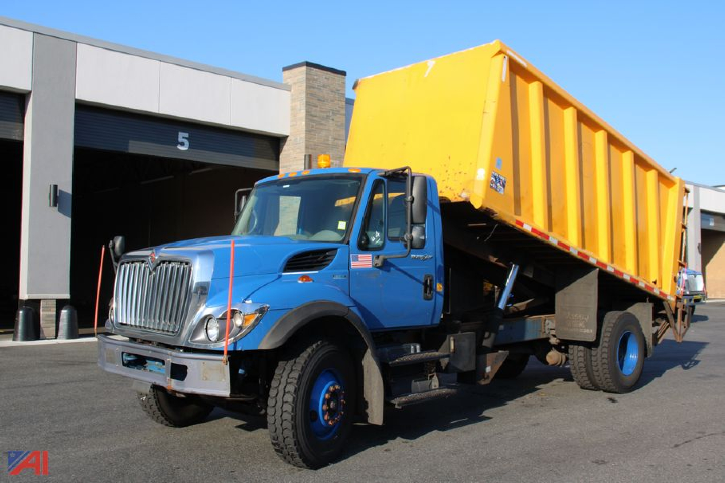 Dump truck with blue cab and yellow dump bed in service bay area showing International WorkStar 7400 model.