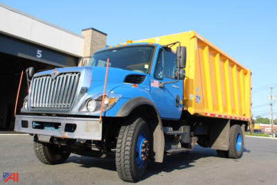 Dump truck showing blue cab and yellow dump bed, International WorkStar 7400, front grille, large tires, side mirrors, and operating lights.